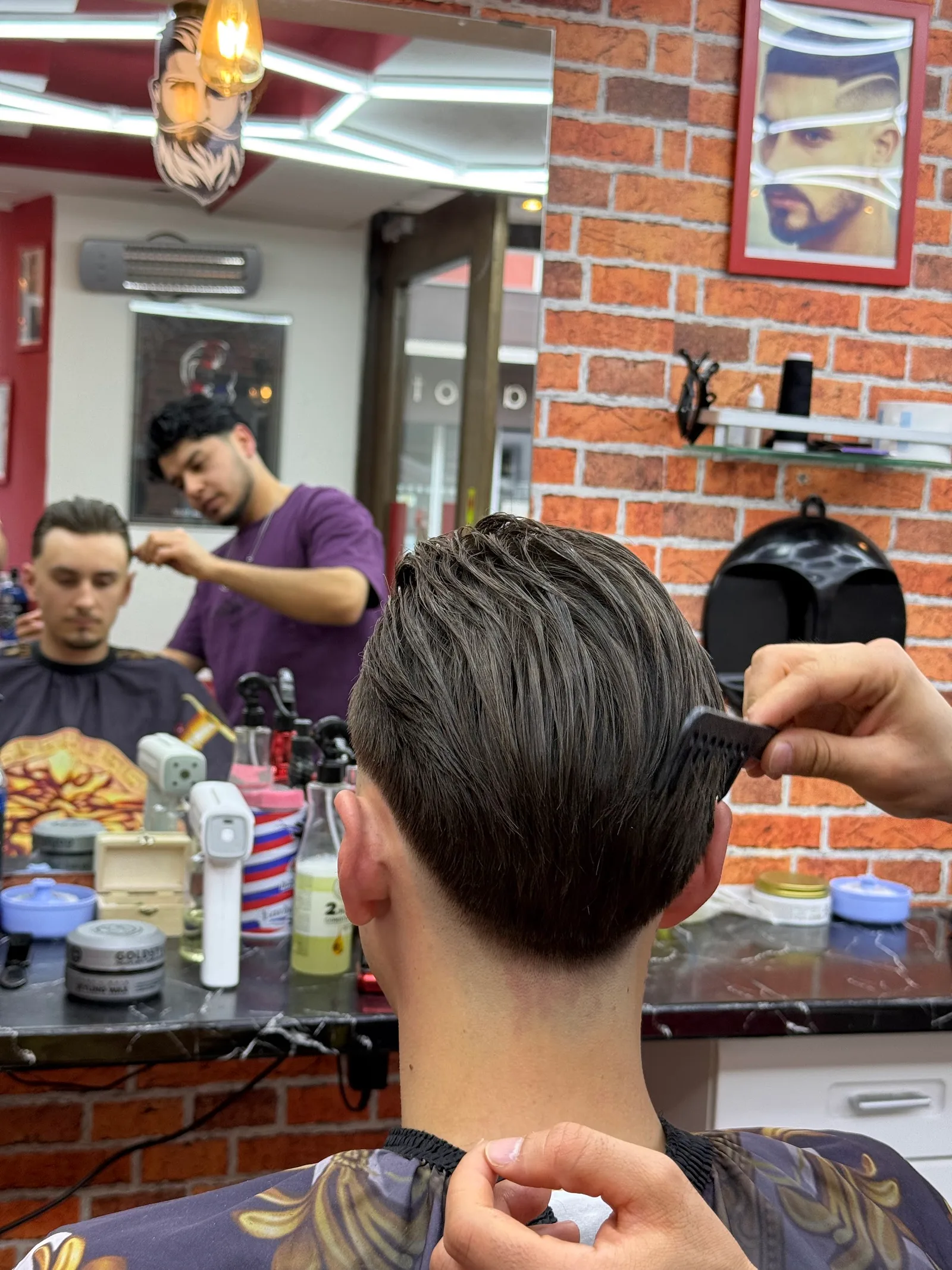 Fertiger Herrenschnitt von hinten, ein Barbier kämmt das Deckhaar nach