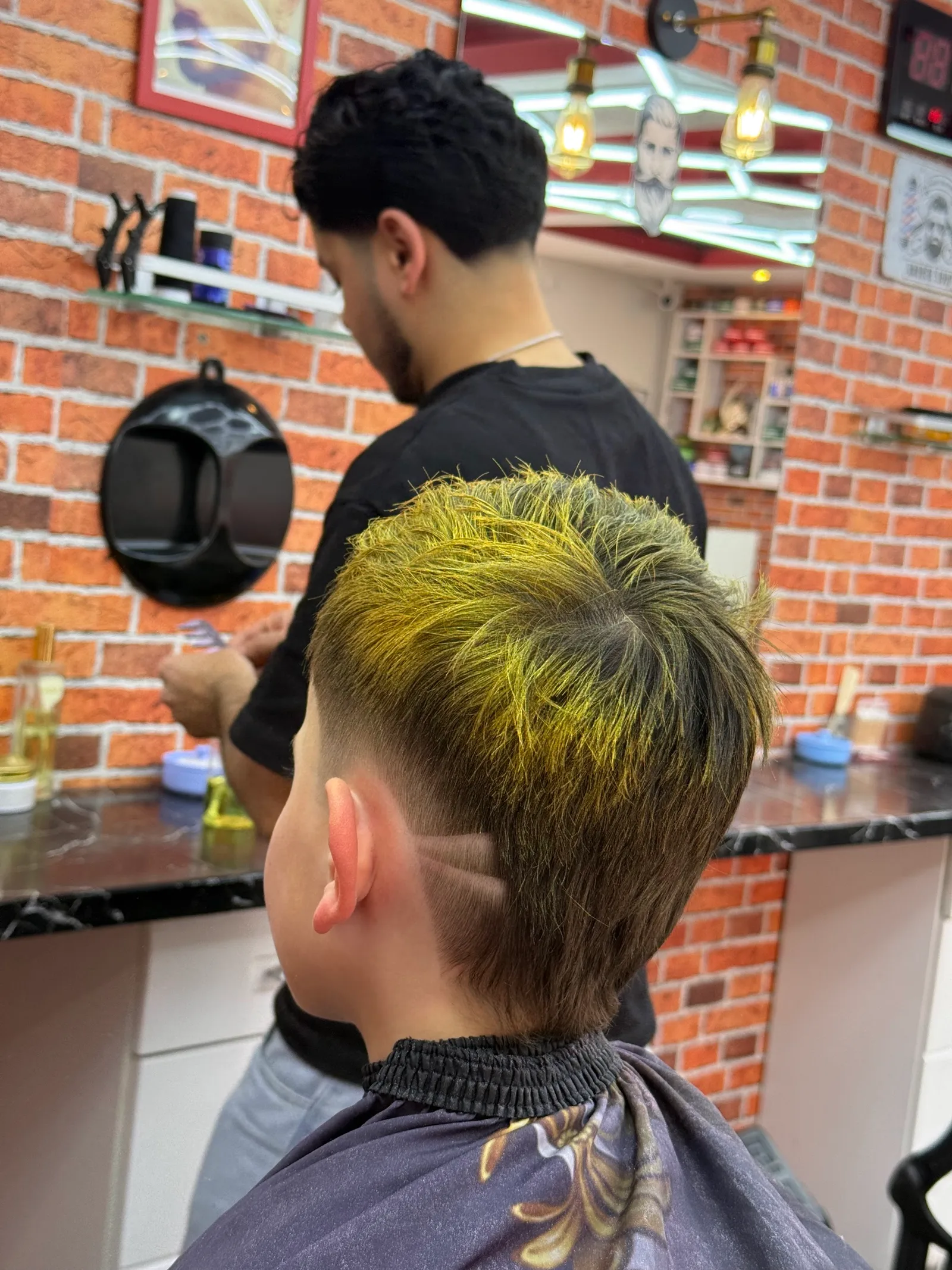 Blond gefärbtes Deckhaar mit weichem Übergang und einer eingeschnittenen Linie über dem Ohr